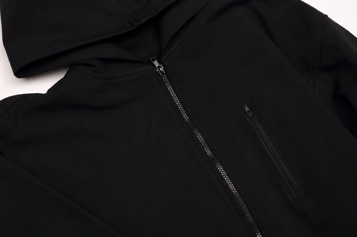 Detalle de materiales y acabado premium de chamarra Softshell Noir con gorro.